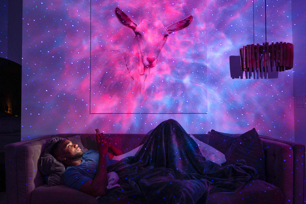 man relaxing under blisslights evolve smart multicolor galaxy projecter in pink and blue