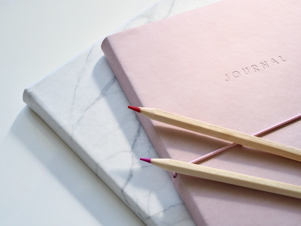 pink and white journals with pencils