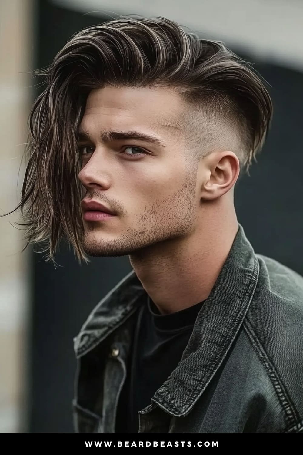 Side profile of a young man with a Disconnected Undercut, a striking style within men's short on sides, long on top haircuts. The long top is swept dramatically to one side, creating a bold contrast with the closely shaved sides, highlighting the sharp disconnect that defines this modern, edgy look.