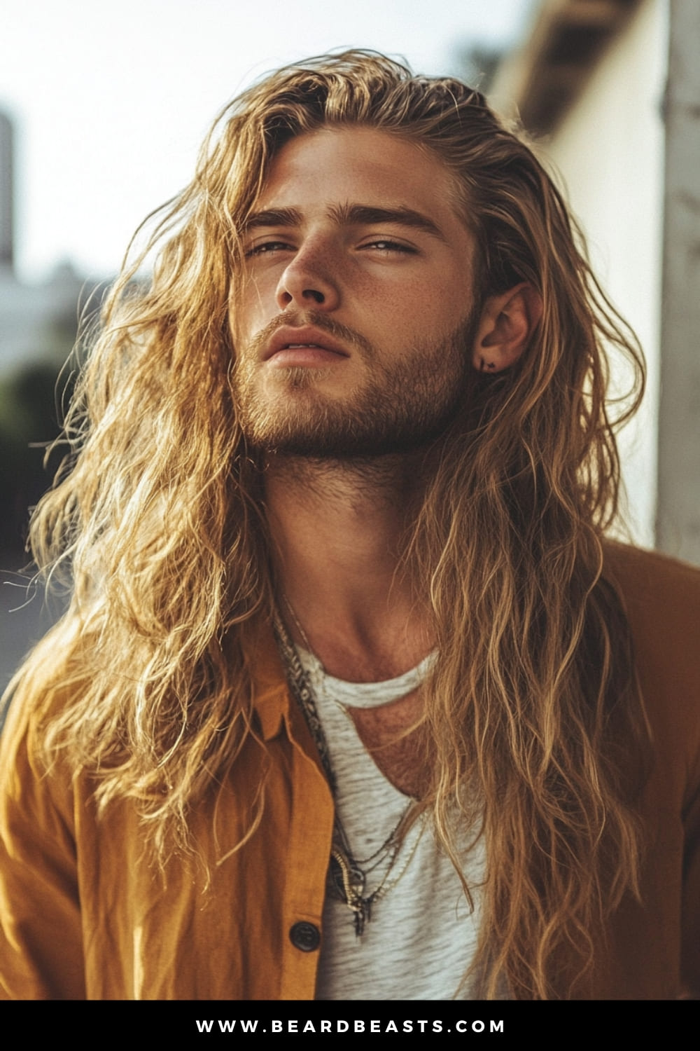 Man with long, loose wavy hair and a light beard, exuding a carefree, sun-kissed look. This style captures a laid-back, bohemian aesthetic, making it a perfect representation of men's hairstyles for long hair that highlights natural texture and effortless cool.