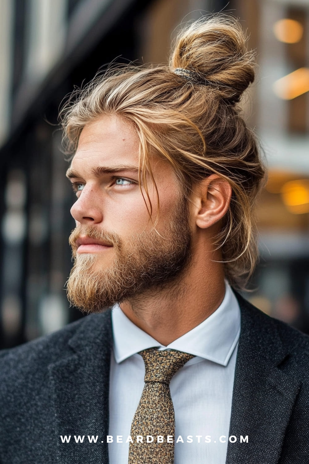 Side view of a man with a man bun and a full beard. This is one of the best long hairstyles for men with round faces, as the updo adds height and creates a more elongated face shape, while the beard provides balance and structure. A stylish and refined option for those with longer hair.