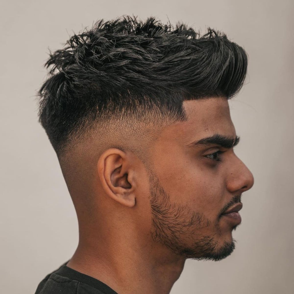A side profile of a man with a stylish quiff haircut, perfect for guys with smaller head shapes. The hairstyle features a textured, voluminous top with a gradual skin fade on the sides, creating a balanced and proportionate look. The quiff adds height, making it a suitable choice for men aiming to enhance their facial structure. This haircut is trendy and ideal for those with smaller head shapes looking to add dimension to their appearance.
