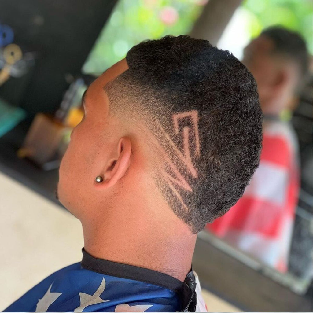 Side view of a Short Burst Fade haircut featuring a bold geometric hair design etched into the fade. The haircut transitions smoothly from a clean skin fade near the ears to a textured top, adding depth and contrast. The sharp line design adds a modern, edgy twist to the classic burst fade style. Perfect for men looking to make a statement with their hairstyle.