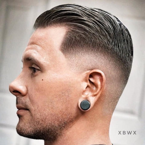 Side profile of a man with a Short Slicked Back haircut, featuring neatly combed back hair with a subtle fade on the sides. The sleek, polished short hairstyle for men highlights the natural shine of the hair, creating a refined and sophisticated look that’s perfect for both formal and casual settings.