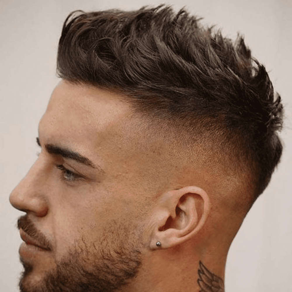 Man with a high fade haircut featuring a spiky top. The hairstyle showcases a clean high fade on the sides and back, contrasting with the voluminous, spiky hair on top. Perfect for a bold and edgy look, this spiky top high fade is ideal for trendy men's hairstyles in 2024.